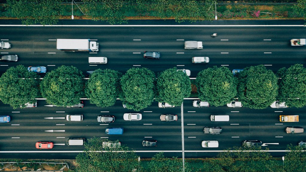 Bird's eye view of highway with trees in middle.