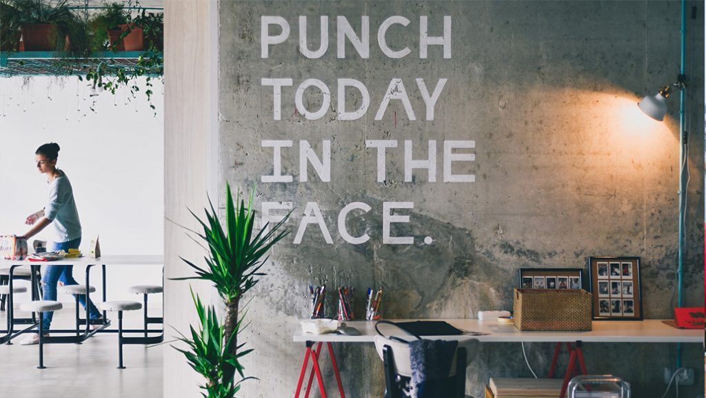Wall in a room with "Punch Today in the Face" written on it.