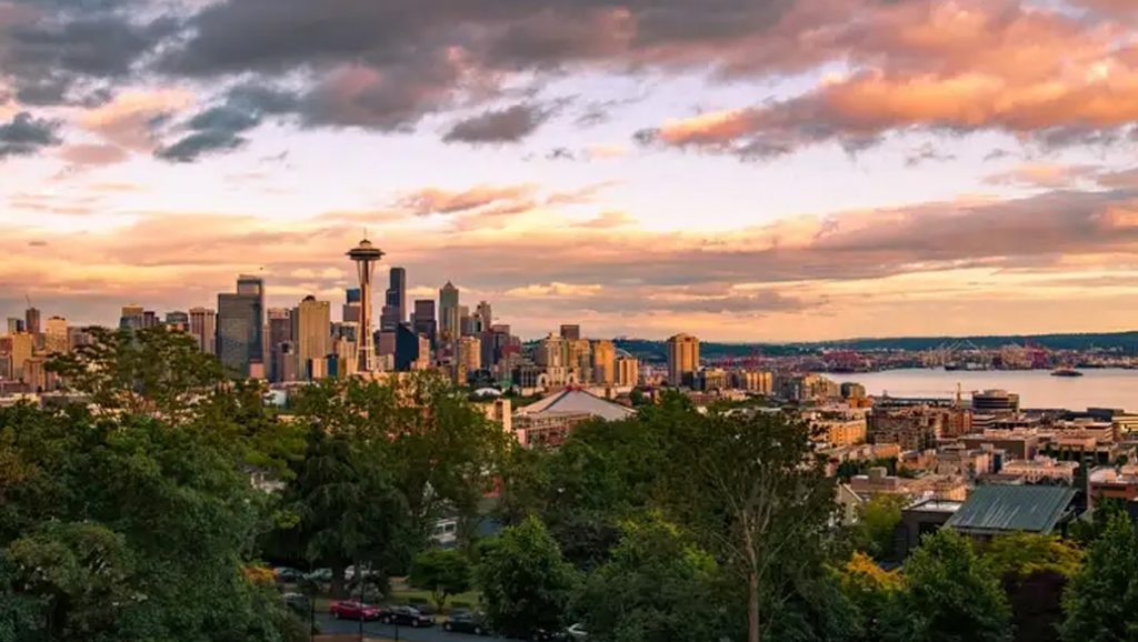 Seattle at sunset with trees in the foreground.